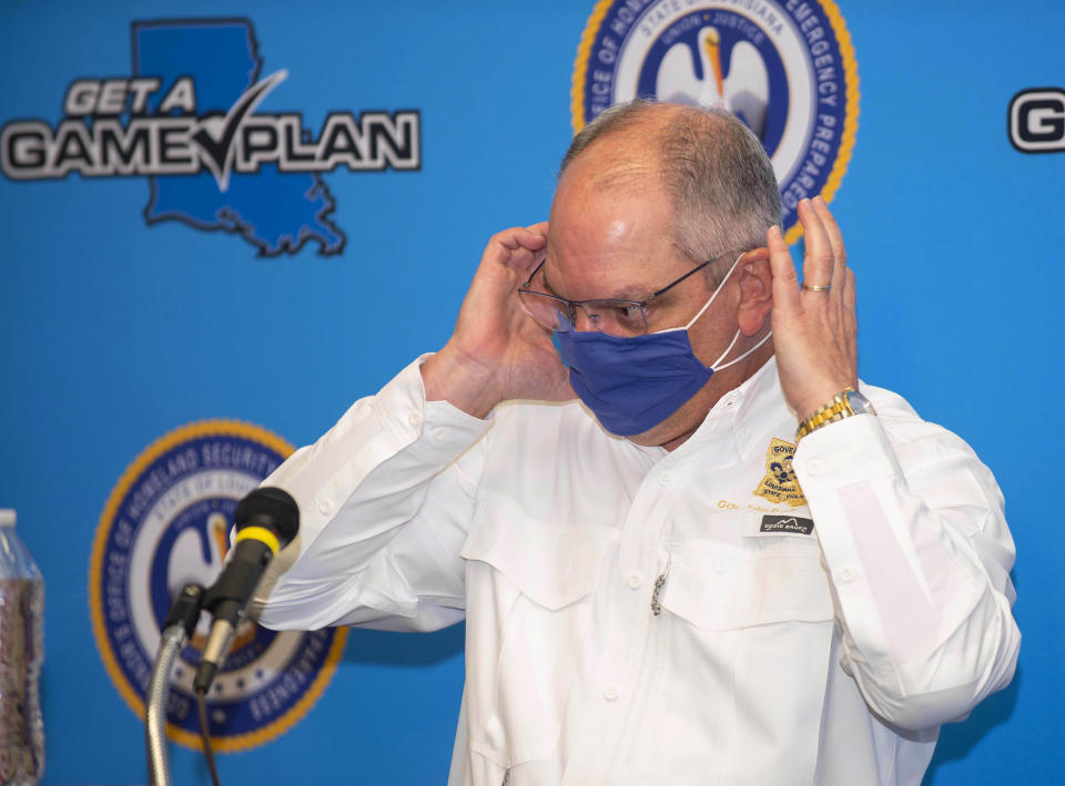 Louisiana Gov. John Bel Edwards puts his face mask back on at the conclusion of a press conference at Louisiana State Police Training Academy, Thursday, Sept. 10, 2020, in Baton Rouge, La. Edwards says the state will ease various restrictions on public gatherings aimed at preventing the spread of COVID-19 — but he's withholding details for a day. Edwards said Thursday that Louisiana will move to “Phase Three” of restrictions after current restrictions expire Friday. (Travis Spradling/The Advocate via AP)