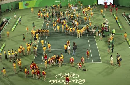 2016 Rio Olympics - Tennis - Victory Ceremony - Men's Singles Victory Ceremony - Olympic Tennis Centre - Rio de Janeiro, Brazil - 14/08/2016. Volunteers are seen on the court after a match between Juan Martin Del Potro (ARG) of Argentina and Andy Murray (GBR) of Britain. REUTERS/Kevin Lamarque