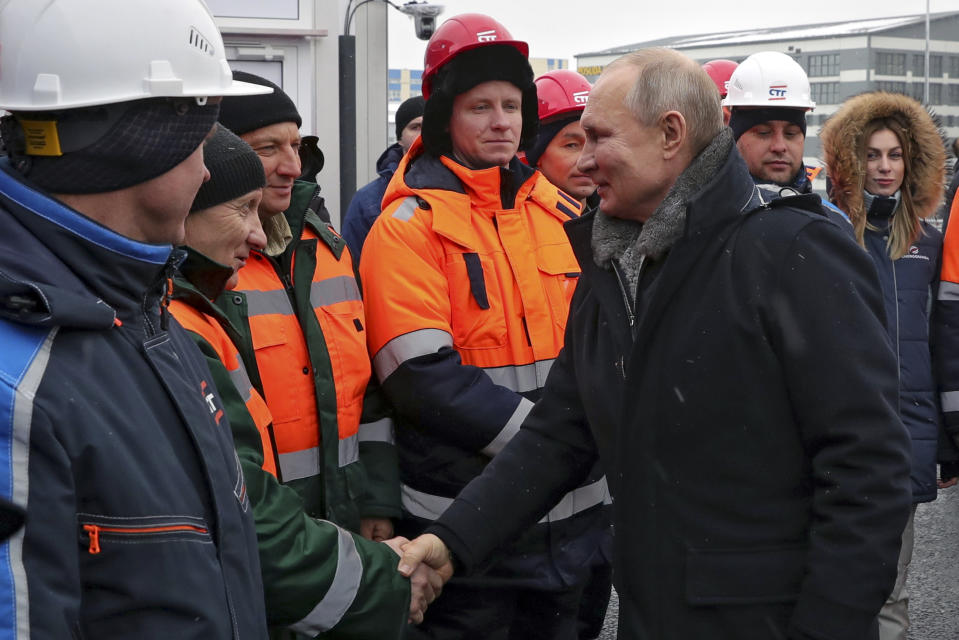 Russian President Vladimir Putin, right, greets workers as he attends an opening ceremony of the road junction of the M-10 "Russia" highway, connecting Moscow and St. Petersburg, in Khimki outside Moscow, Russia, Tuesday, Jan. 26, 2021. (Mikhail Klimentyev, Sputnik, Kremlin Pool Photo via AP)