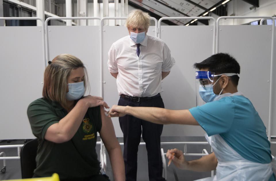 FILE - In this Monday Jan. 11, 2021 file photo, Britain's Prime Minister Boris Johnson watches first responder Caroline Cook receiving an injection of a Covid-19 vaccine at Ashton Gate Stadium in Bristol, England. When the World Health Organization declared the coronavirus a pandemic one year ago Thursday, March 11 it did so only after weeks of resisting the term and maintaining the highly infectious virus could still be stopped. A year later, the U.N. agency is still struggling to keep on top of the evolving science of COVID-19, to persuade countries to abandon their nationalistic tendencies and help get vaccines where they’re needed most. (Eddie Mulholland/Pool via AP, file)