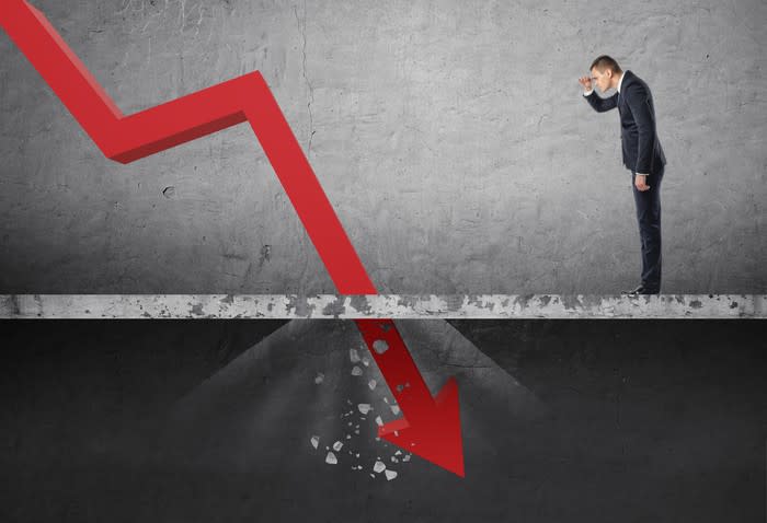 Man looking at red line chart plunging through floor