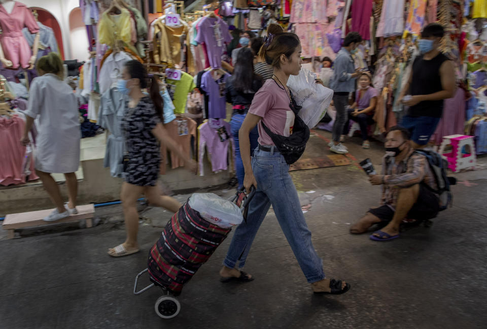 FILE - In this Aug. 6, 2020, file photo, a shopper pulls a cart full of clothing at a market in Bangkok, Thailand. Shortages of power, computer chips and other parts, soaring shipping costs and shutdowns of factories to battle the pandemic are taking a toll on Asian economies. (AP Photo/ Gemunu Amarasinghe, File)