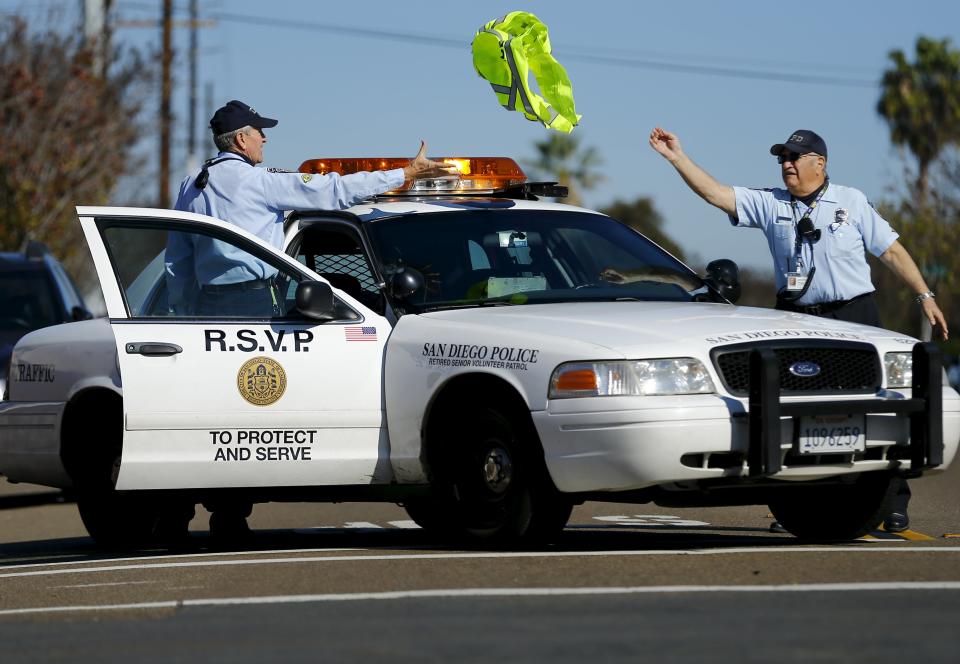 88-year-old Ed Robles (R) throws a safety vest to partner Dick Engel after directing traffic at the scene of a car accident during their Retired Senior Volunteer Patrol in San Diego, California, United States February 4, 2015. (REUTERS/Mike Blake)