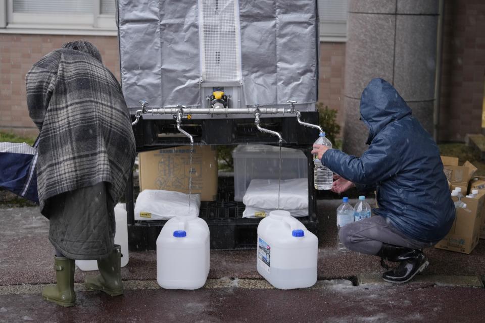 Evacuees from a deadly earthquake receive water supply at an evacuation center in Wajima in the Noto peninsula facing the Sea of Japan, northwest of Tokyo, Sunday, Jan. 7, 2024. Monday's temblor decimated houses, twisted and scarred roads and scattered boats like toys in the waters, and prompted tsunami warnings. (AP Photo/Hiro Komae)