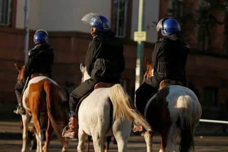 Riot police officers ride horses as they patrol the streets in Bulawayo