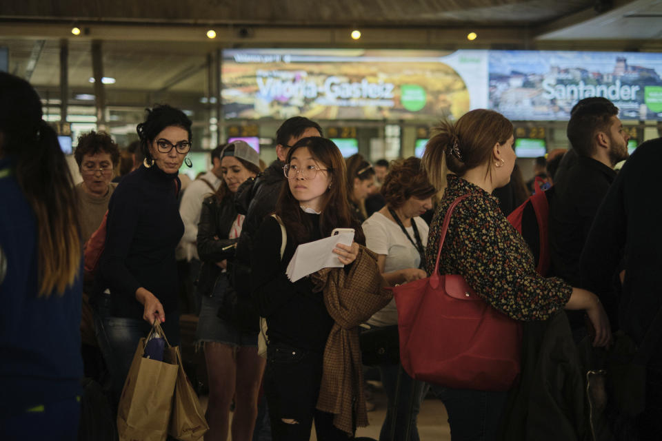 Passengers queue in the airport in Santa Cruz de Tenerife, Spain, Sunday, Feb. 23, 2020. Flights leaving Tenerife have been affected after storms of red sand from Africa's Saharan desert hit the Canary Islands. (AP Photo/Andres Gutierrez)