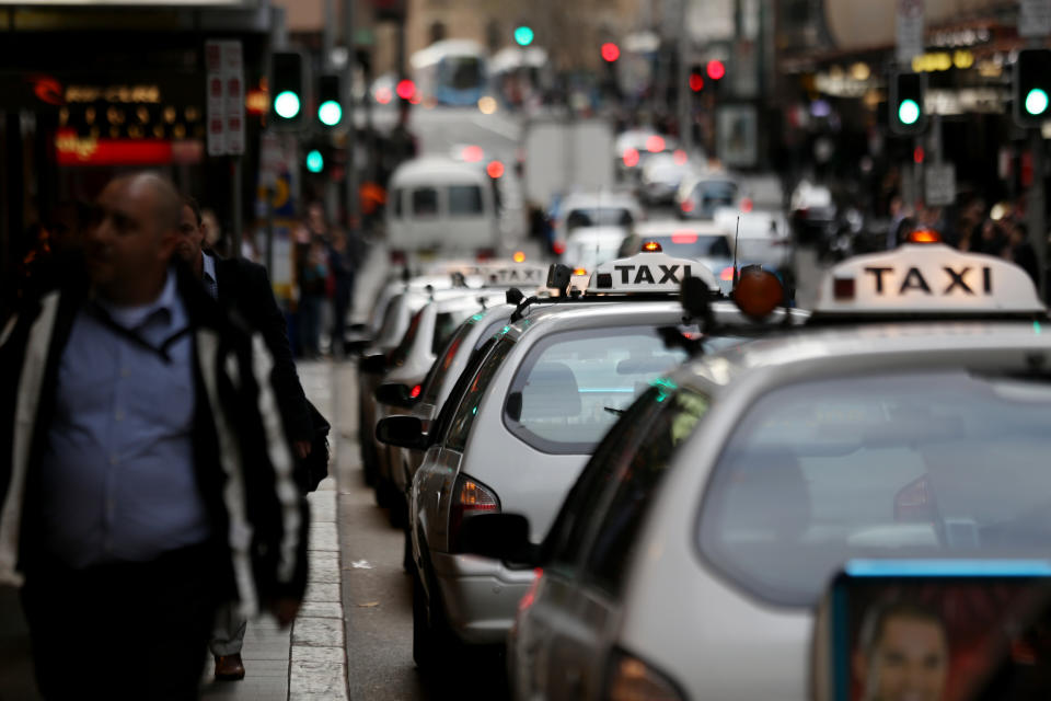 A line of Taxis in Sydney can be seen as people walk past.