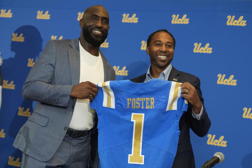 New UCLA NCAA college football head coach DeShaun Foster, left, poses with UCLA athletic director Martin Jarmond.