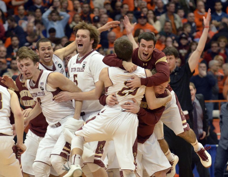 Boston College players celebrate after defeating Syracuse 62-59 in overtime as Syracuse's Trevor Cooney, right, walks off the court following an NCAA college basketball game in Syracuse, N.Y., Wednesday, Feb. 19, 2014. (AP Photo/Kevin Rivoli)