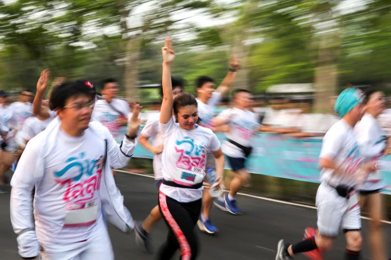 Runners flash the three-finger salute as they attend the "Run Against Dictatorship" event at a Public park in Bangkok