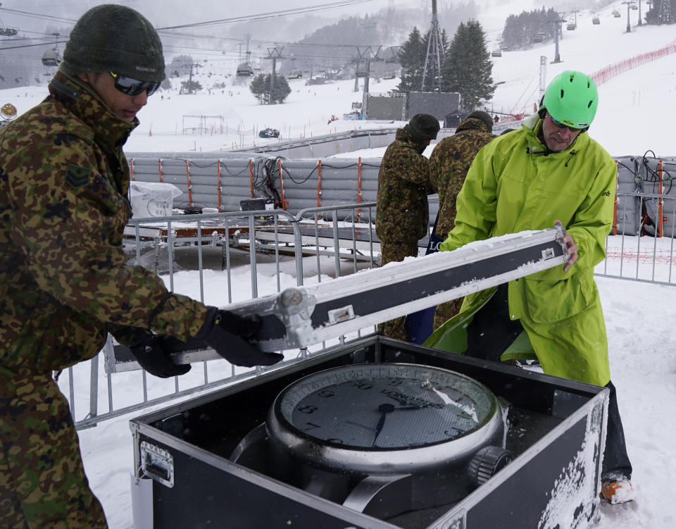 Japan Self-Defense Forces members and event staff officials put away the Longines clock after it was announced that the men's slalom race has been cancelled due to weather conditions during the 2020 Audi FIS Alpine Ski World Cup at Naeba Ski Resort in Yuzawa, Niigata prefecture, northern Japan, Sunday, Feb. 23, 2020. (AP Photo/Christopher Jue)
