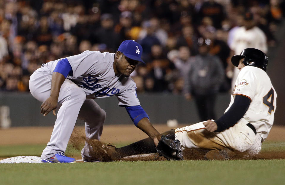 San Francisco Giants' Hunter Pence, right, is safe at third base past the tag attempt from Los Angeles Dodgers third baseman Juan Uribe after a wild pitch during the sixth inning of a baseball game on Tuesday, April 15, 2014, in San Francisco. (AP Photo/Marcio Jose Sanchez)