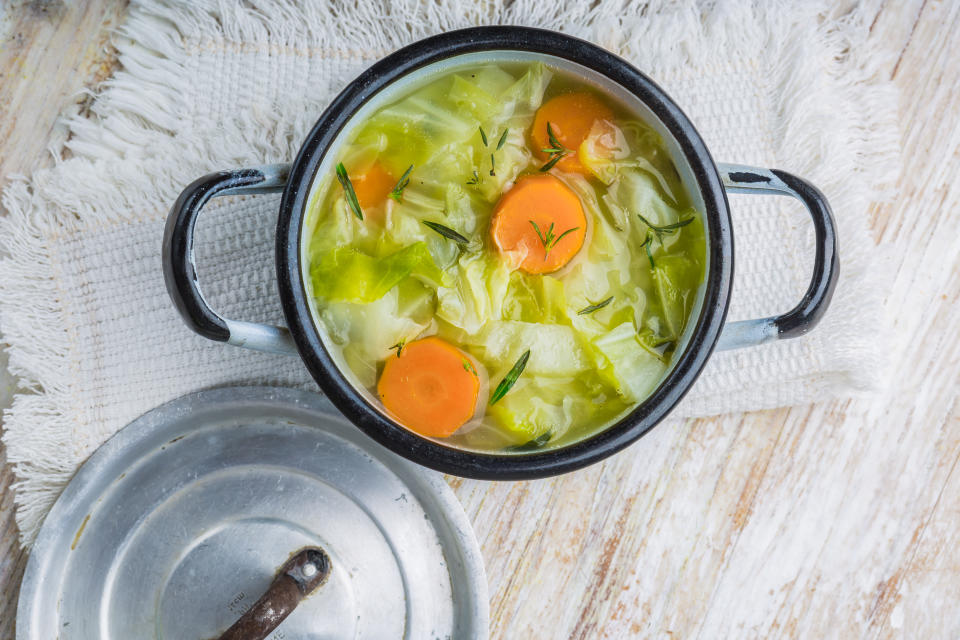 Fresh cabbage soup in a pot on white wooden table