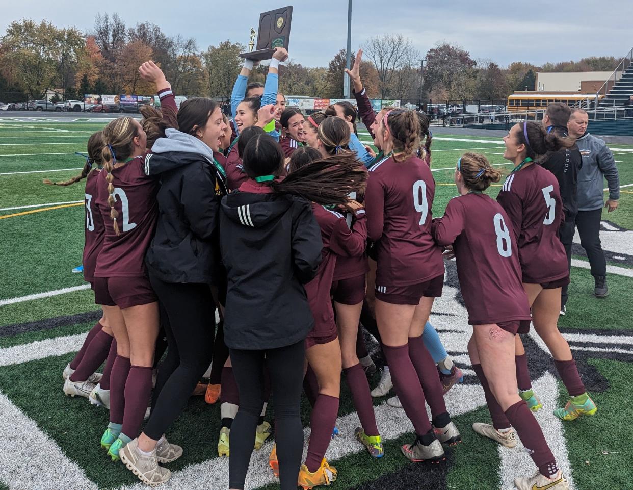 The Walsh Jesuit girls soccer team mobs keeper Adri Lika and the regional championship trophy after beating Magnificat 2-1.