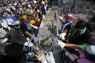 Anti-government protesters remove the razor wire from the entrance of the compound of metropolitan police headquarters, the site of fierce clashes with police over the last few days in Bangkok December 3, 2013. Thailand's government ordered police to stand down and allow protesters into state buildings on Tuesday, removing a flashpoint for clashes and effectively bringing an end to days of violence in Bangkok in which five people have died. REUTERS/Damir Sagolj (THAILAND - Tags: CIVIL UNREST POLITICS)