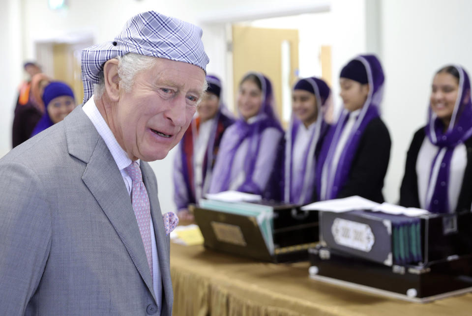 Britain's King Charles III smiles next to children who are learning Punjabi and traditional music inside the Langar Hall during his visit to the newly built Guru Nanak Gurdwara, in Luton, England, Tuesday, Dec. 6, 2022. (Chris Jackson/Pool Photo via AP)