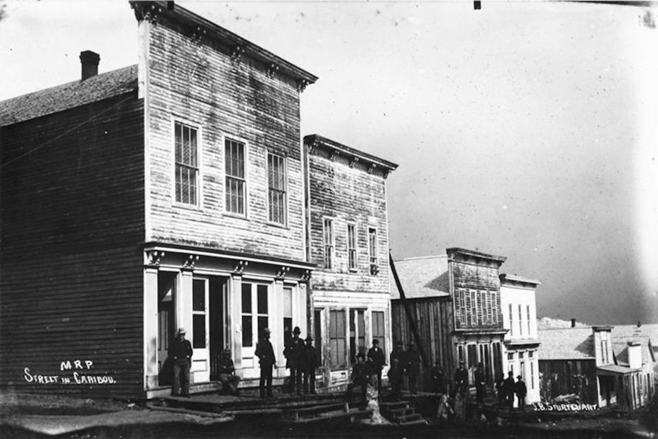A street in Caribou. Men standing in front of stores.
