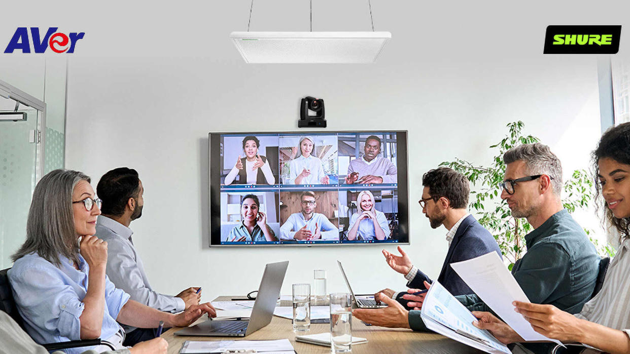  AVer and Shure have teamed up for AI voice-tracking shown here in a small conference room with happy people conducting a video call. . 