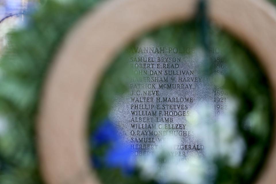 The names of officers who are honored on the Police Memorial statue can be see through a wreath during the annual Police Memorial Ceremony on Tuesday, May 16, 2023.