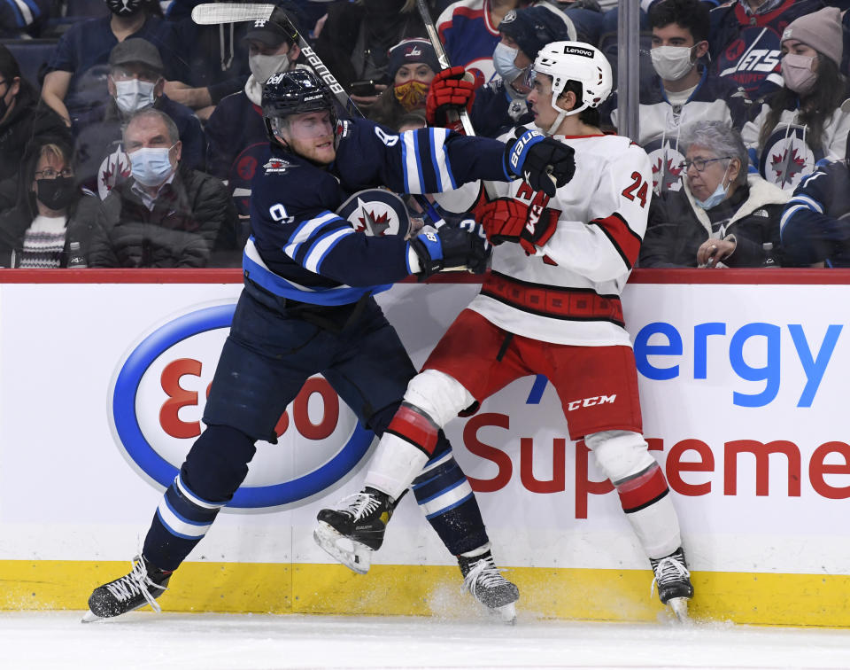 Winnipeg Jets' Andrew Copp (9) checks Carolina Hurricanes' Seth Jarvis (24) during the second period of an NHL game in Winnipeg, Manitoba, Tuesday, Dec. 7, 2021. (Fred Greenslade/The Canadian Press via AP)