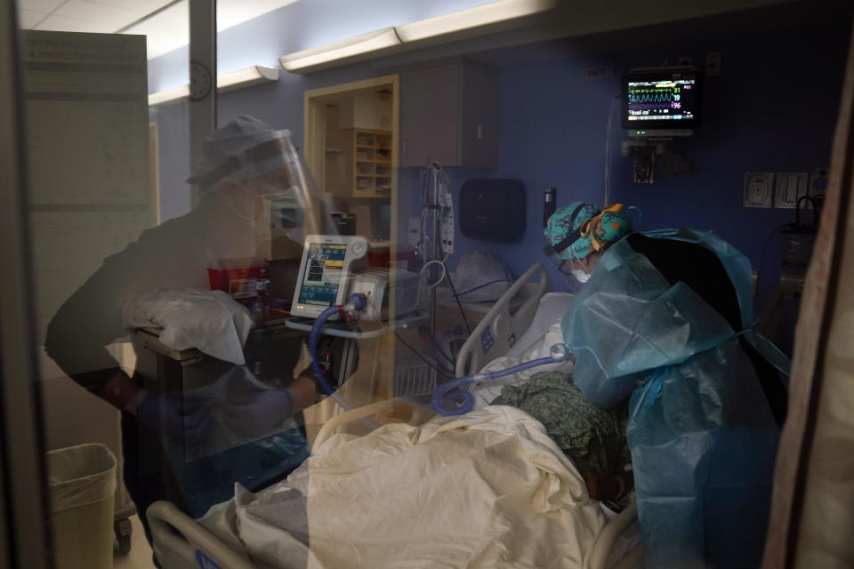 FILE - In this Jan. 7, 2021, file photo, registered nurses Kyanna Barboza, right, tends to a COVID-19 patient as Kobie Walsh puts on her PPE at St. Joseph Hospital in Orange, Calif. Coronavirus deaths in the U.S. hit another one-day high on Tuesday, Jan. 12, 2021, at over 4,300 with the country’s attention focused largely on the fallout from the deadly uprising at the Capitol. (AP Photo/Jae C. Hong, File)