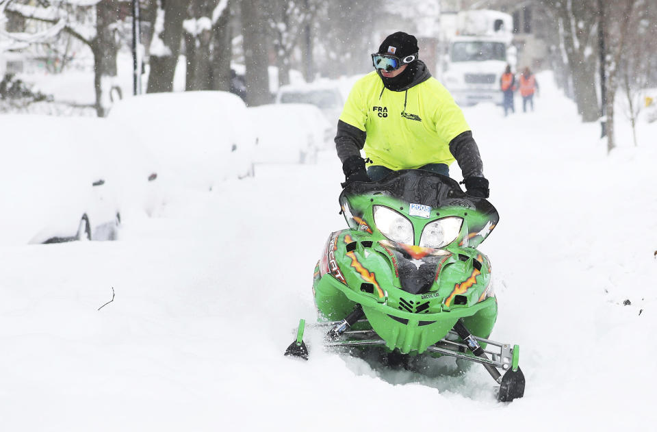 Alex King rides a snowmobile through a neighborhood in Buffalo, N.Y.'s Elmwood Village on Monday, Dec. 26, 2022. (Joseph Cooke/The Buffalo News via AP)