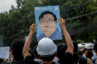 A pro-democracy activist displays a poster featuring an image of recently detained protest leader Parit Chiwarak during a demonstration at Kaset intersection, suburbs of Bangkok, Thailand, Monday, Oct. 19, 2020. Thailand's embattled Prime Minister Prayuth Chan-ocha said Monday that there were no plans to extend a state of emergency outside the capital, even as student-led protests calling for him to leave office spread around the country. (AP Photo/Sakchai Lalit)