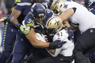 Seattle Seahawks defensive end Rasheem Green (94) brings down New Orleans Saints running back Alvin Kamara (41) during the first half of an NFL football game, Monday, Oct. 25, 2021, in Seattle. (AP Photo/Ted S. Warren)