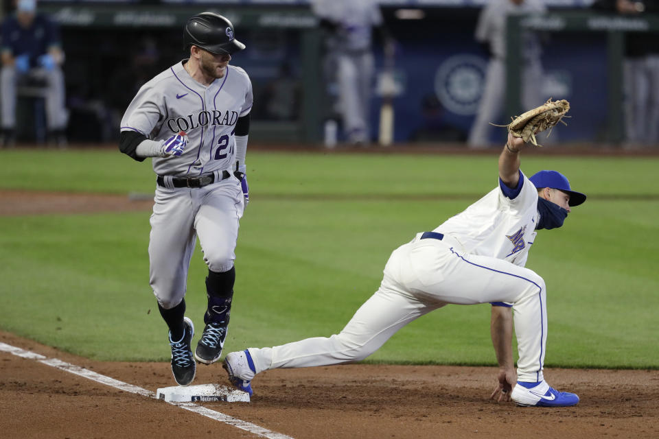 Colorado Rockies' Trevor Story, left, looks at Seattle Mariners first baseman Evan White after grounding out in the third inning of a baseball game Sunday, Aug. 9, 2020, in Seattle. (AP Photo/Elaine Thompson)
