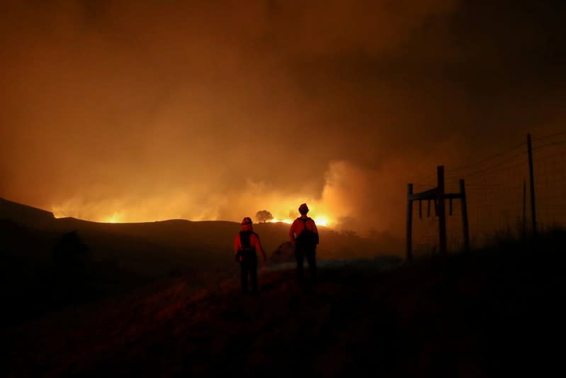 FILE PHOTO: Two firefighters monitor the Kincade fire, near Geyserville, California