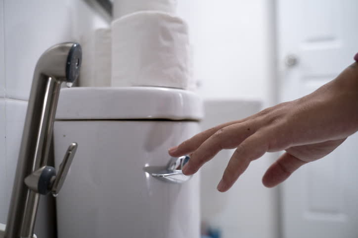 Person reaching for a toilet flush lever