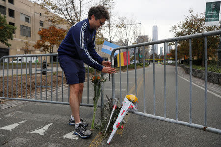 Jeffrey Raven, 55, places the flags of Belgium and Argentina above flowers laid for victims of Tuesday's attack outside a police barricade on the bike path next to West Street a day after a man driving a rented pickup truck mowed down pedestrians and cyclists on a bike path alongside the Hudson River in New York City, in New York, U.S. November 1, 2017. REUTERS/Shannon Stapleton