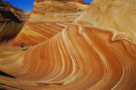 <p>A hiker walks on a rock formation known as The Wave in the Vermilion Cliffs National Monument in Arizona. (Photo: Corbis/Getty Images) </p>