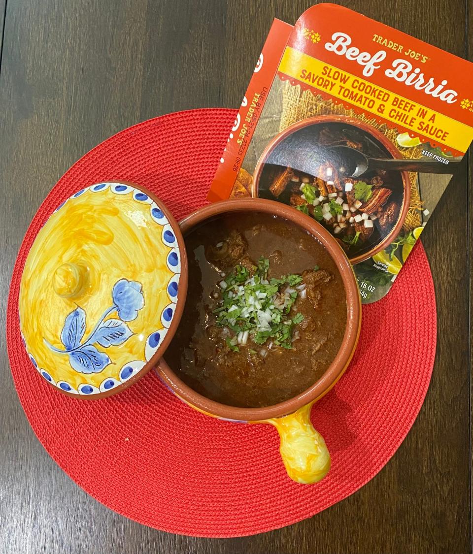 Trader Joe's Beef Birria in a Mexican pot with onions and cilantro.
