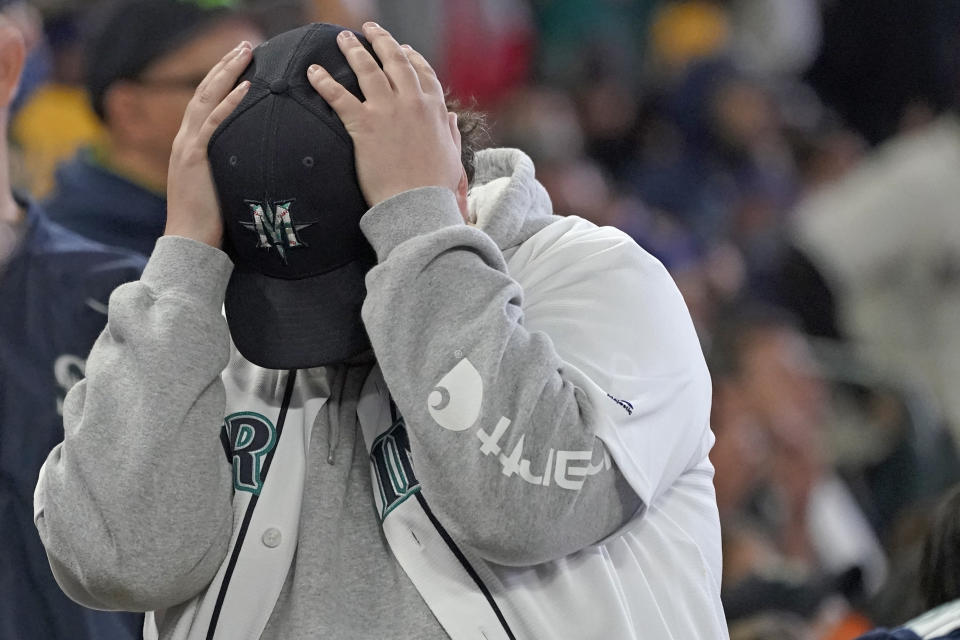 A Seattle Mariners fan reacts after Los Angeles Angels' Jack Mayfield was ruled safe stealing second base after the initial call of out was overturned on review during the sixth inning of a baseball game, Sunday, Oct. 3, 2021, in Seattle. (AP Photo/Ted S. Warren)