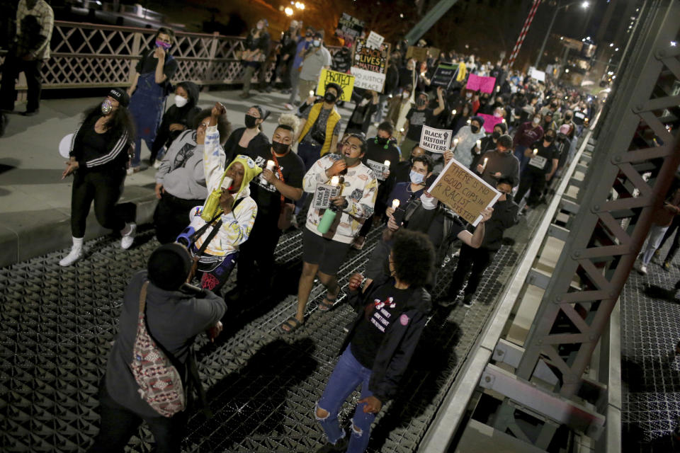 A group marches towards the Hawthorne Bridge after meeting at Salmon Street Springs and listening to several Black and Indigenous speakers talk, Friday, April 16, 2021, in Portland, Ore. Police in Portland, said Saturday they arrested several people after declaring a riot Friday night when protesters smashed windows, burglarized businesses and set multiple fires during demonstrations that started after police fatally shot a man while responding to reports of a person with a gun. (Dave Killen/The Oregonian/The Oregonian via AP)