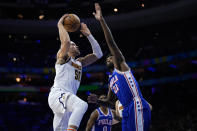 Denver Nuggets' Aaron Gordon, left, goes up for a shot against Philadelphia 76ers' Joel Embiid during the first half of an NBA basketball game, Tuesday, Jan. 16, 2024, in Philadelphia. (AP Photo/Matt Slocum)