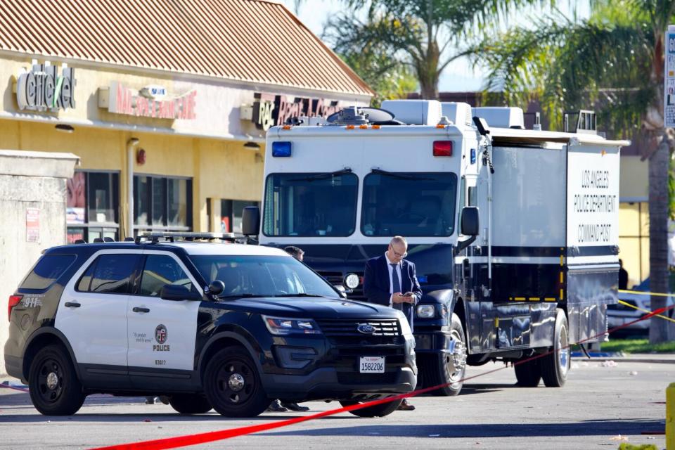 Investigators and police vehicles in a shopping center parking lot