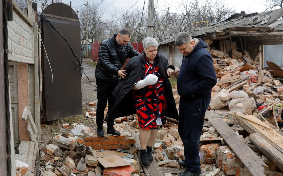 Local resident Svetlana Boiko, 66, who was injured in recent shelling, is assisted while walking out of her destroyed house in the course of Russia-Ukraine conflict in Donetsk, Russian-controlled Ukraine, March 12, 2023. - REUTERS/Alexander Ermochenko