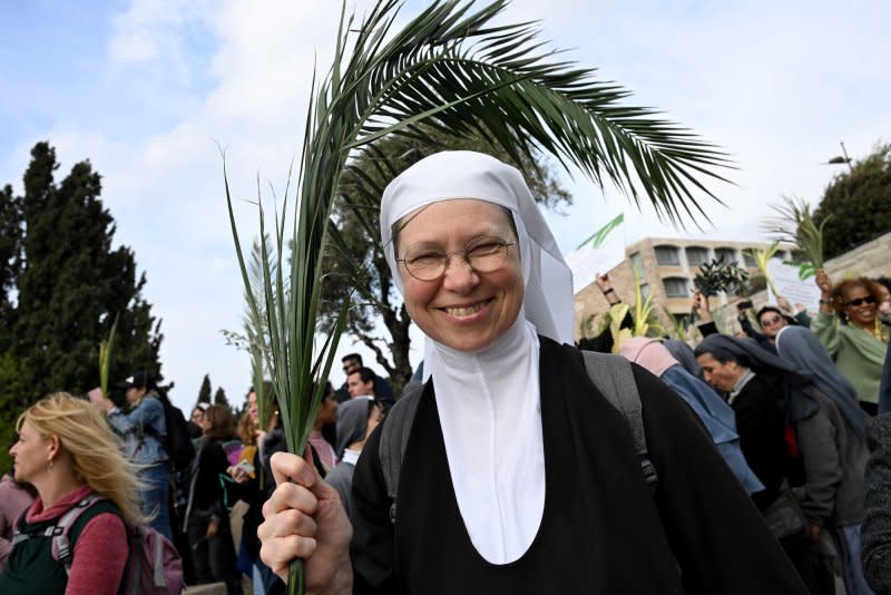 A nun holds a palm branch during the traditional Palm Sunday procession on the Mt. Of Olives, overlooking the Old City of Jerusalem, East Jerusalem, on Sunday, March 24, 2024. Photo by Debbie Hill/UPI