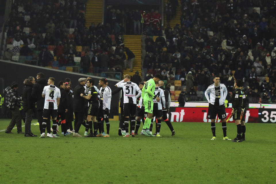 Referee Fabio Maresca, eight from left, match officials, right, and Udinese's players gather as the Italian Serie A soccer match between Udinese and AC Milan is suspended, at the Friuli stadium in Udine, Italy, Saturday, Jan. 20, 2024. Racist abuse aimed at AC Milan goalkeeper Mike Maignan prompted a top-tier Italian league game at Udinese to be suspended briefly during the first half. Maignan left the field after the insults which followed a goal for Milan. (Andrea Bressanutti/LaPresse via AP)