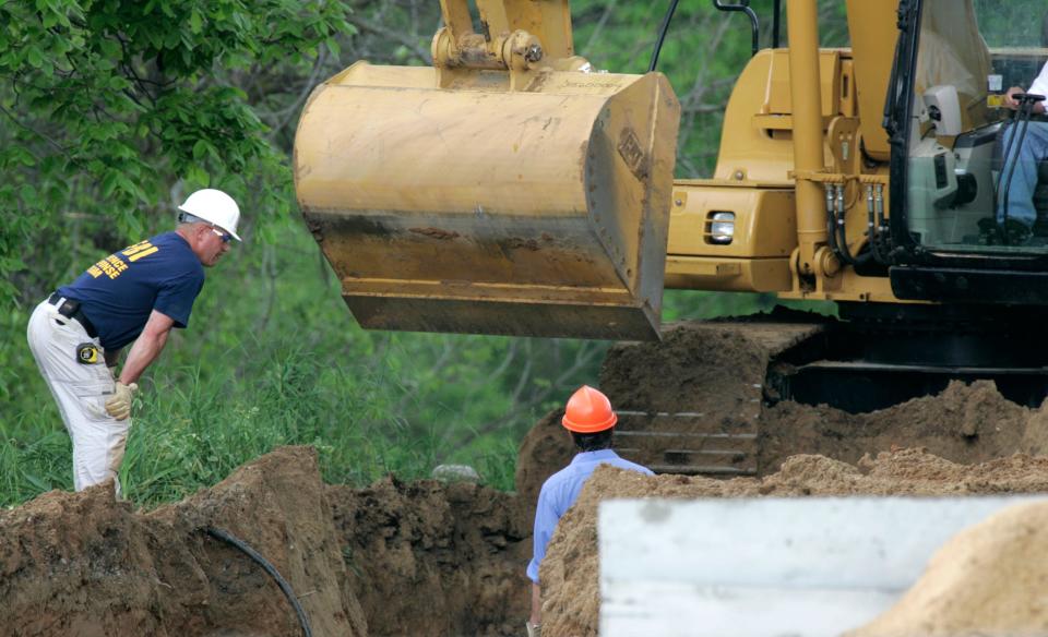 An unidentified worker and a Federal Bureau of Investigation evidence response team member, left, examine a dig site where a barn once stood at a horse farm in Milford Township, Mich., where FBI agents investigating Jimmy Hoffa's 1975 disappearance were working on May 26, 2006. The Teamsters leader had vanished from a restaurant in Oakland County's Bloomfield Township, about 20 miles away.