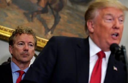 U.S. Senator Rand Paul (R-KY) listens as U.S. President Donald Trump speaks before signing an executive order making it easier for Americans to buy bare-bones health insurance plans and circumvent Obamacare rules at the White House in Washington, U.S., October 12, 2017.  REUTERS/Kevin Lamarque