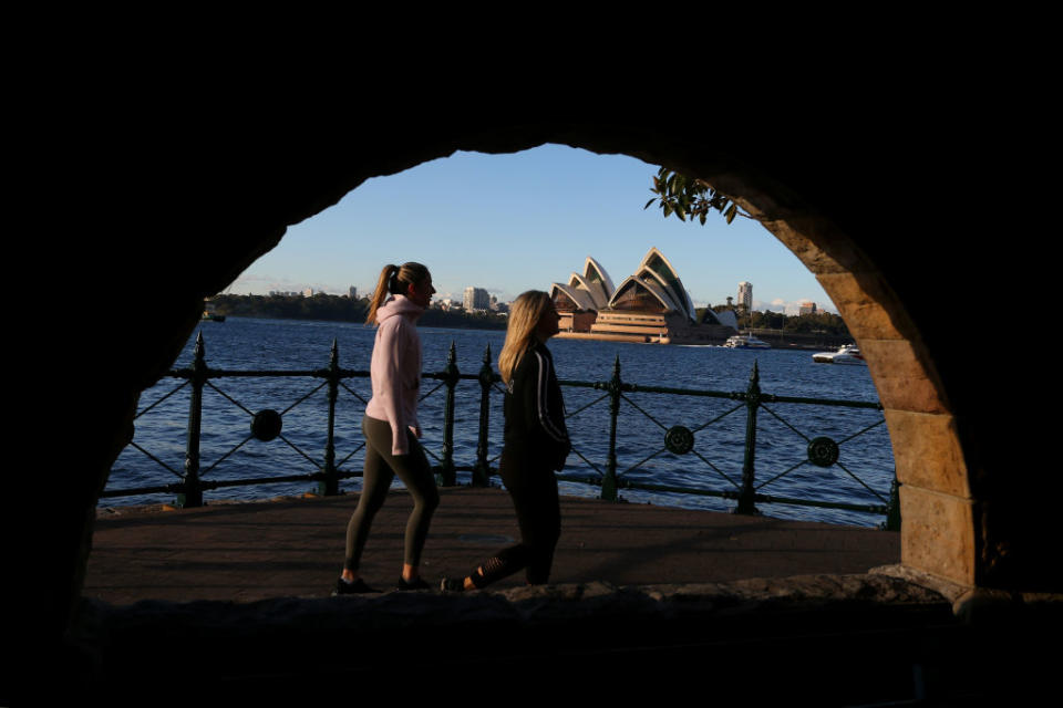 People exercise along the boardwalk at Milsons Point as the Opera House is seen across the harbour on in Sydney, Australia.