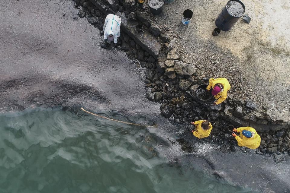 TOPSHOT - An aerial view shows people scooping leaked oil on August 10, 2020, from the MV Wakashio bulk carrier that had run aground at the beach in Bambous Virieux, southeast Mauritius. (Photo by - / L'Express Maurice / AFP) (Photo by -/L'Express Maurice/AFP via Getty Images)