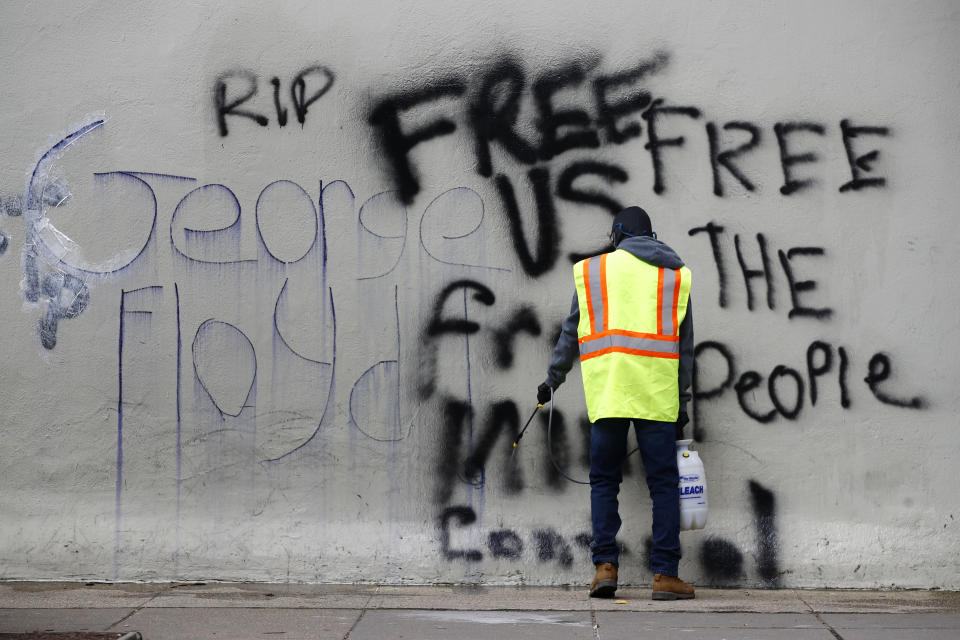 A worker removes graffiti from a building, Tuesday, June 2, 2020, in Washington, following protests over the death of George Floyd, who died after being restrained by Minneapolis police officers. (AP Photo/Patrick Semansky)