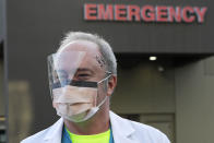 Dr. Stephen Anderson, a physician who works in the Emergency Department at the MultiCare Auburn Medical Center in Auburn, Wash., wears a mask and face shield as he poses for a photo before starting his shift, Tuesday, March 17, 2020, in Auburn, Wash., south of Seattle. Anderson said he writes messages on his shields to identify them as his, and this morning he chose the phrase "Stay Safe." “There just are not enough masks to go around at my hospital,” said Dr. Anderson. "I've got a two-day supply of masks so we're trying to be conservative. You get one in the morning. You clean it and reuse it." (AP Photo/Ted S. Warren)