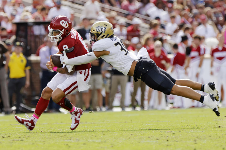 Central Florida linebacker Kam Moore, right, tackles Oklahoma quarterback Dillon Gabriel who carries the ball in the first half of an NCAA college football game, Saturday, Oct. 21, 2023, in Norman, Okla. (AP Photo/Nate Billings)