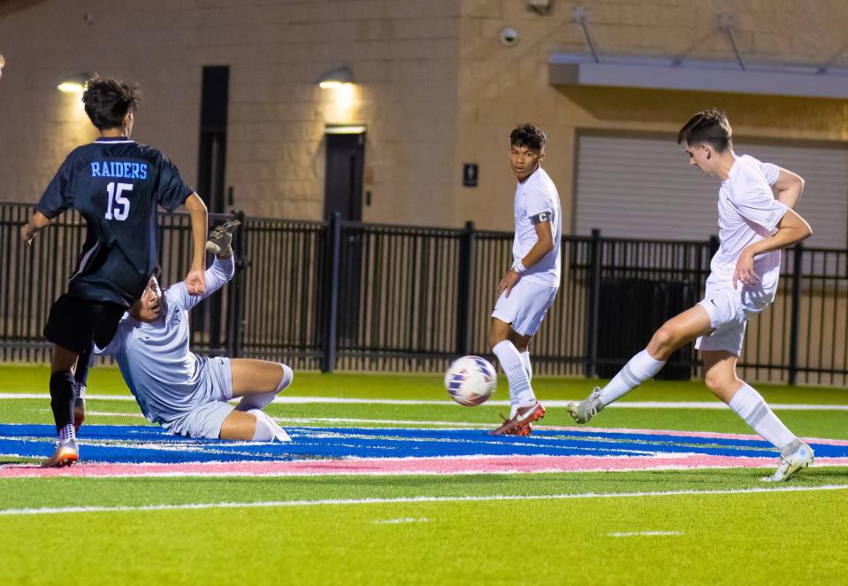 Hendrickson's Jacob Youngkin scores past diving Northeast goalkeeper Alan Garcia in the first half. Garcia later made a brilliant save during the shootout, helping the Raiders win the Class 5A bi-district playoff at the Pfield.