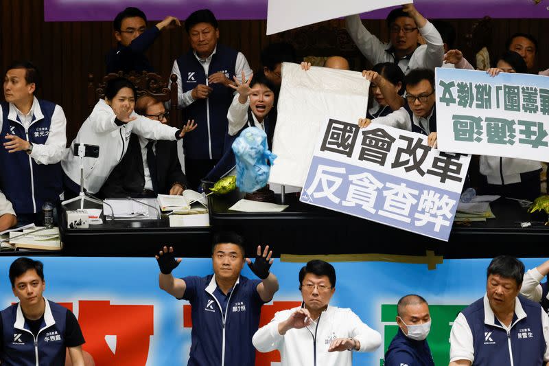 Lawmakers from the the largest opposition party Kuomintang (KMT) try to block plastic bags, some with a text reading “trash”, that were thrown by lawmakers from the Democratic Progressive Party (DPP), during a session at the Parliament in Taipei